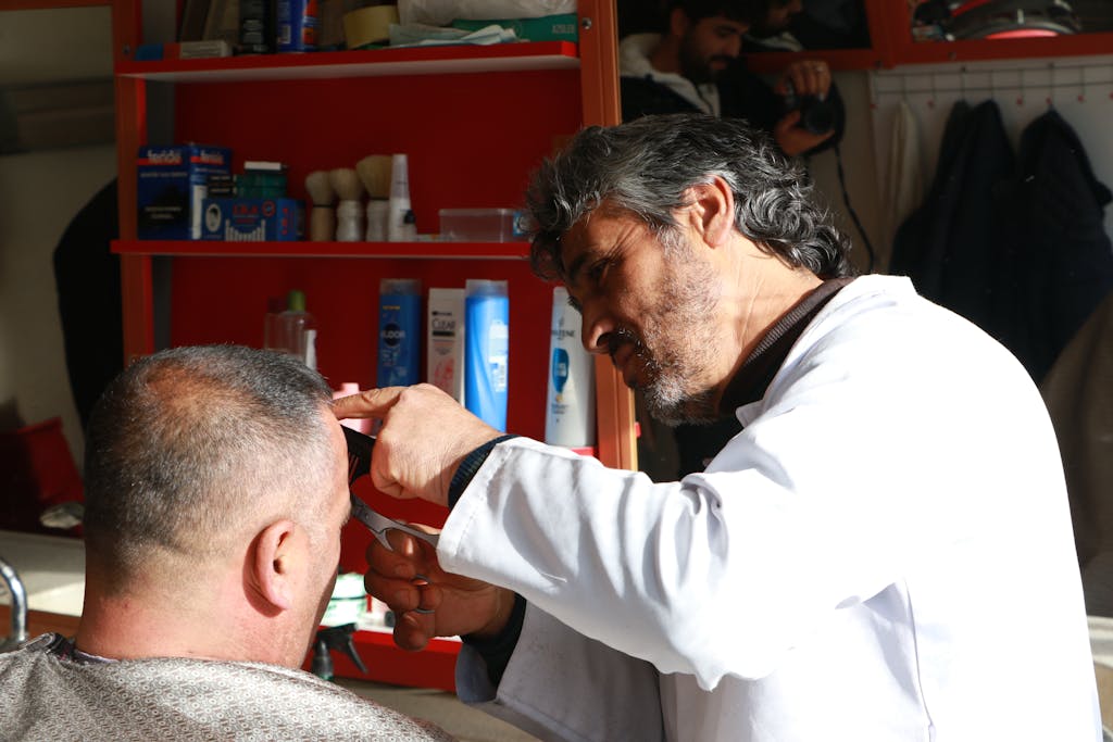 A barber focuses on cutting a customer's hair in a well-equipped barbershop.